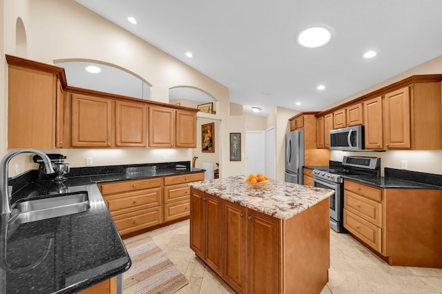 kitchen with lofted ceiling, sink, dark stone counters, a center island, and stainless steel appliances