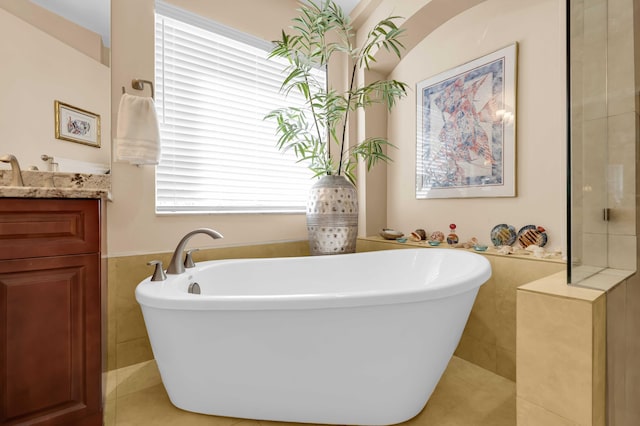 bathroom with a washtub, vanity, and tile patterned floors