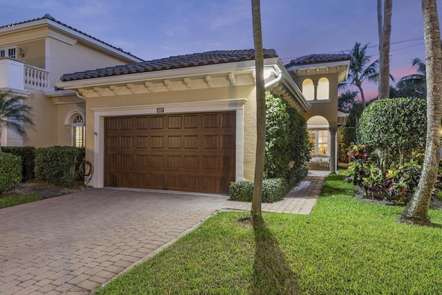 mediterranean / spanish-style home featuring a garage and a lawn