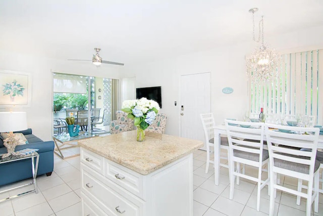 kitchen with a center island, hanging light fixtures, light tile patterned floors, ceiling fan with notable chandelier, and white cabinets