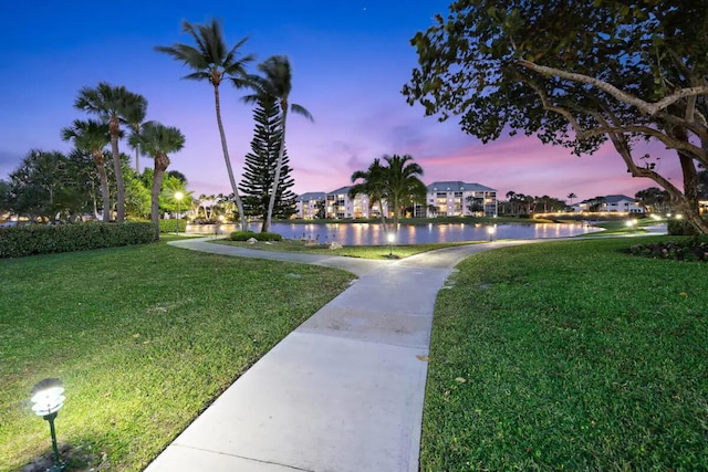 surrounding community with a water view and a lawn