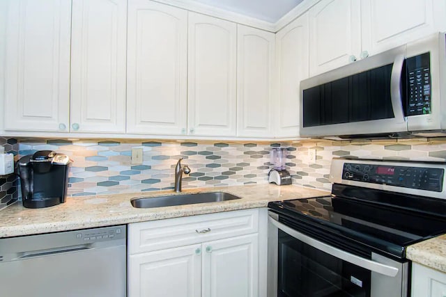 kitchen featuring light stone counters, sink, stainless steel appliances, and white cabinets