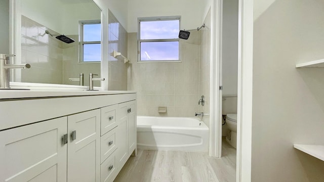 full bathroom with vanity, toilet, tiled shower / bath combo, and hardwood / wood-style floors