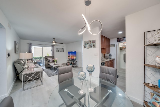 dining area featuring a ceiling fan, baseboards, visible vents, and light wood finished floors