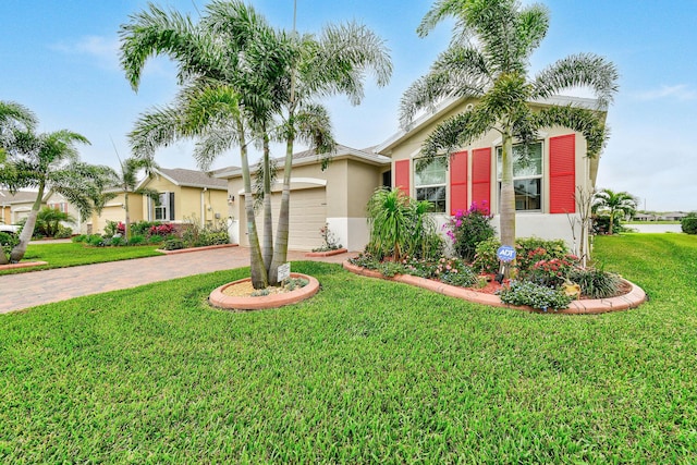 ranch-style house with stucco siding, an attached garage, a front yard, and decorative driveway