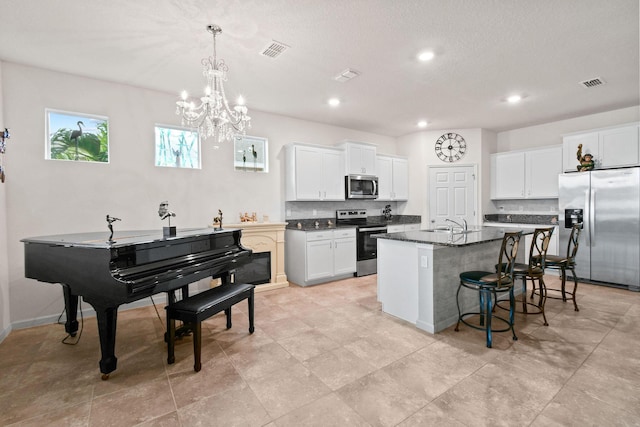 kitchen with stainless steel appliances, visible vents, a kitchen bar, and a center island with sink