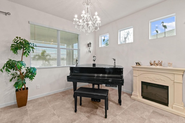 sitting room featuring a glass covered fireplace, baseboards, and an inviting chandelier