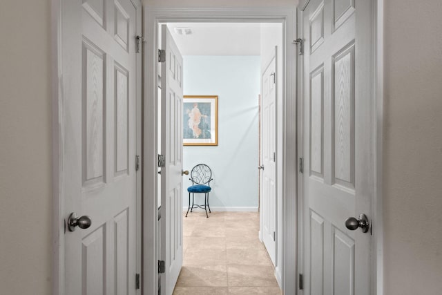 corridor with visible vents, baseboards, and light tile patterned flooring