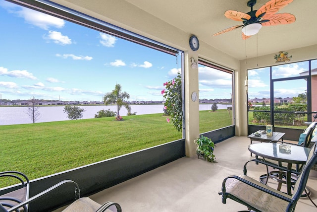 sunroom / solarium with a ceiling fan and a water view
