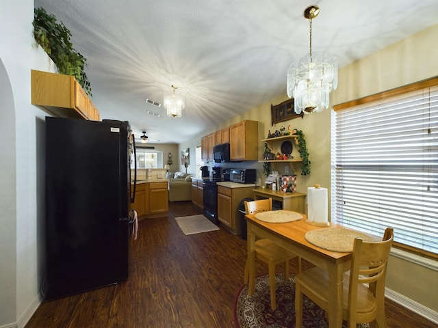 kitchen with decorative light fixtures, dark wood-type flooring, ceiling fan with notable chandelier, and black appliances