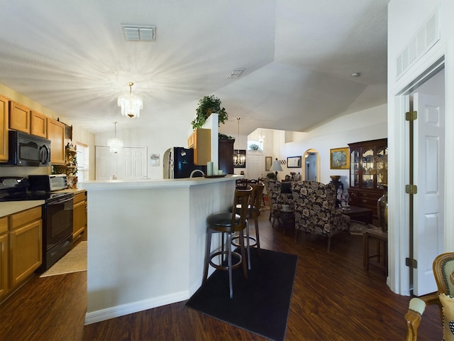 kitchen featuring dark hardwood / wood-style flooring, a kitchen island with sink, hanging light fixtures, and black appliances