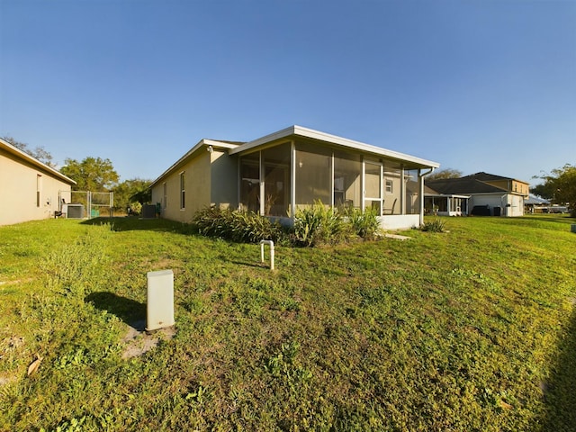 back of house featuring central AC unit, a lawn, and a sunroom