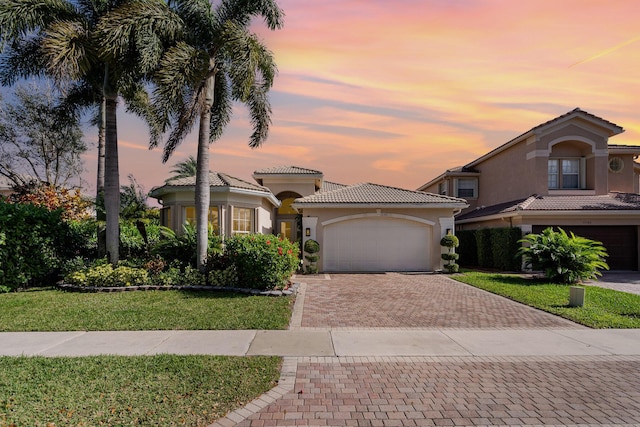 mediterranean / spanish-style home featuring a garage and a lawn