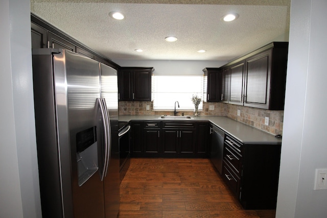 kitchen with sink, dark wood-type flooring, stainless steel appliances, tasteful backsplash, and a textured ceiling