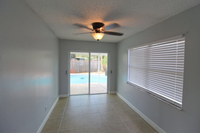 unfurnished room with baseboards, a textured ceiling, ceiling fan, and tile patterned flooring