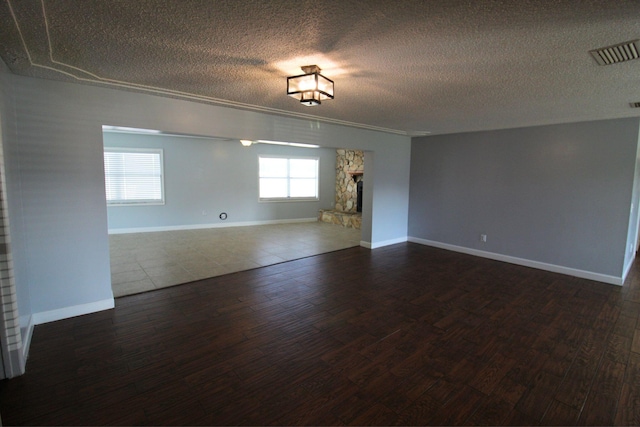 unfurnished room with dark wood-type flooring, a textured ceiling, and visible vents