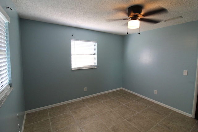 spare room with tile patterned flooring, baseboards, a textured ceiling, visible vents, and a ceiling fan