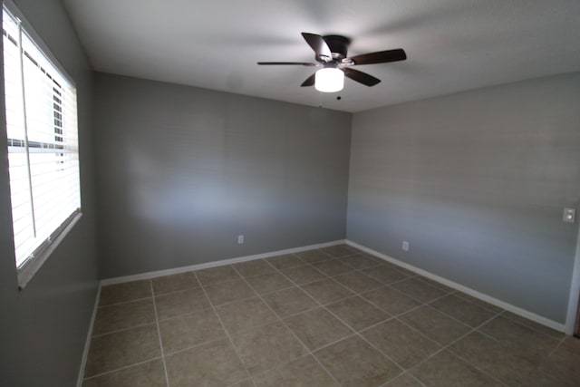 tiled spare room with a ceiling fan and baseboards
