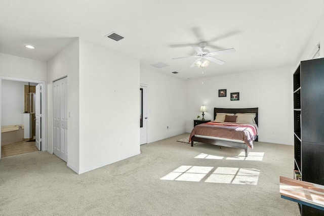 bedroom featuring carpet, ensuite bath, visible vents, and a ceiling fan