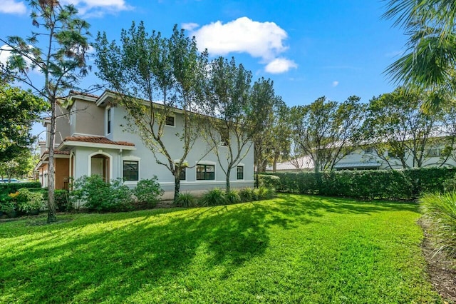 exterior space with a yard, a tiled roof, and stucco siding