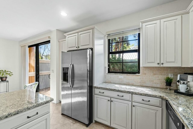 kitchen with stainless steel appliances, light stone counters, decorative backsplash, and light tile patterned floors