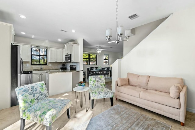 living area with visible vents, ceiling fan with notable chandelier, a wealth of natural light, and recessed lighting