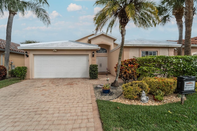 ranch-style house with an attached garage, decorative driveway, and stucco siding