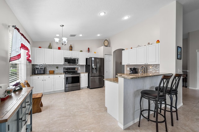 7087 Lombardy St, Boynton Beach, FL 33472 - kitchen featuring lofted ceiling, a peninsula, a notable chandelier, stone countertops, and stainless steel appliances