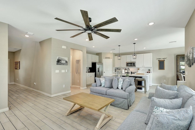 living area with light wood-style floors, recessed lighting, visible vents, and a ceiling fan