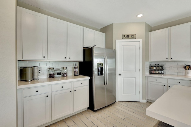 kitchen with light countertops, light wood finished floors, white cabinetry, and stainless steel fridge with ice dispenser