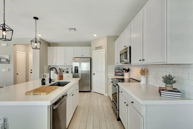 kitchen with stainless steel appliances, visible vents, light wood-style flooring, white cabinets, and a sink