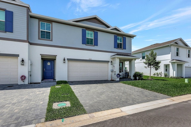 view of front of property featuring an attached garage, a front lawn, decorative driveway, and stucco siding