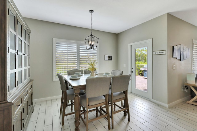 dining room featuring light wood-style flooring, baseboards, and an inviting chandelier