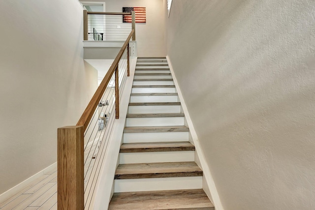 staircase featuring wood finished floors and baseboards