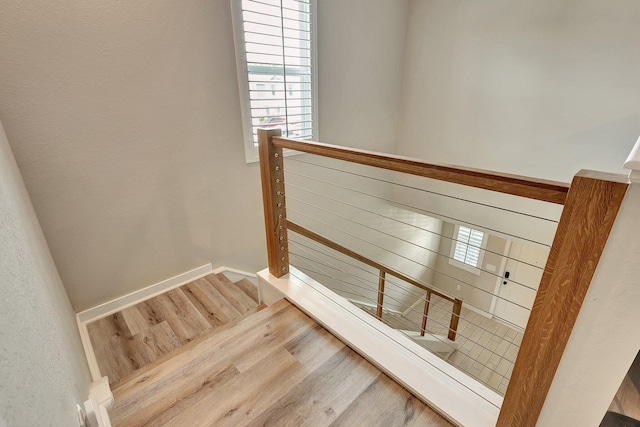 stairway with wood finished floors and baseboards