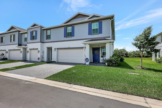 view of property featuring an attached garage, a front lawn, decorative driveway, and stucco siding