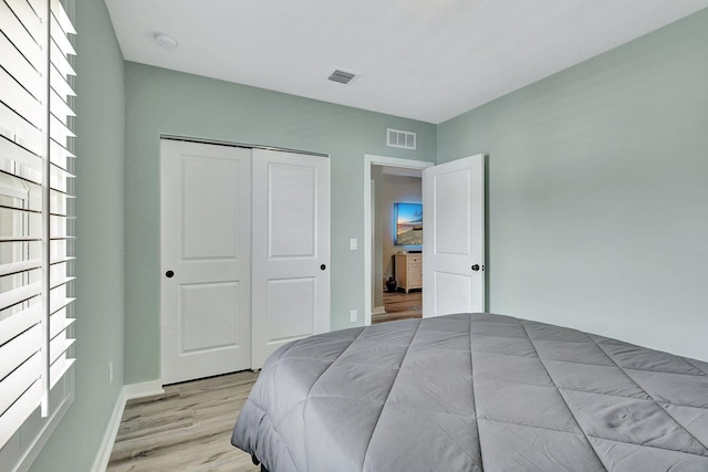 bedroom featuring light wood-type flooring, a closet, and visible vents