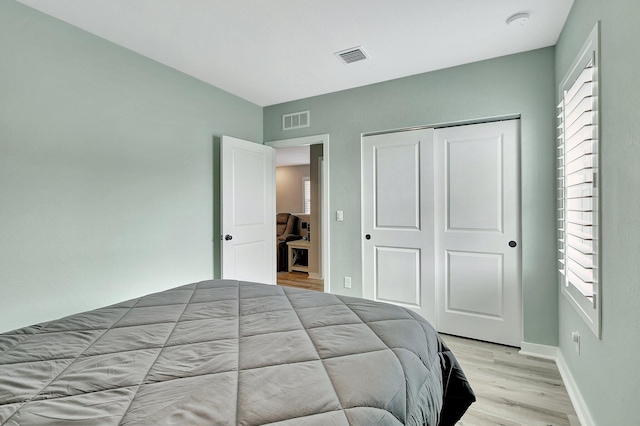 bedroom with light wood finished floors, a closet, visible vents, and baseboards