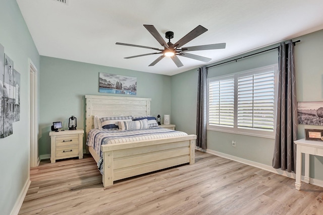 bedroom with light wood finished floors, ceiling fan, and baseboards