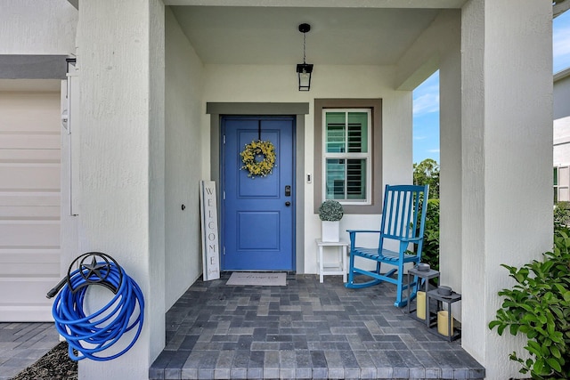 entrance to property with a porch and stucco siding