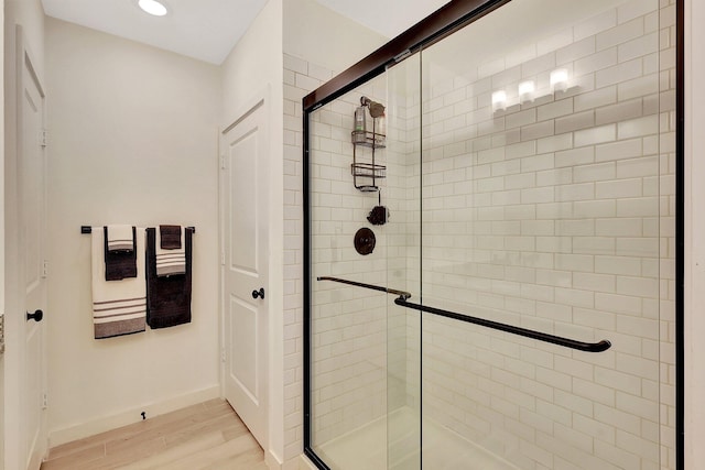 full bathroom featuring a stall shower, wood finished floors, and baseboards