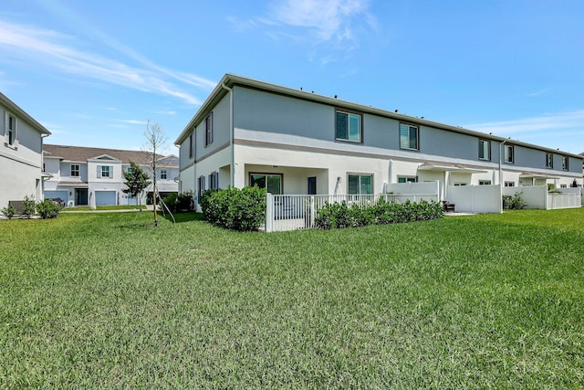 back of property featuring fence, a lawn, and stucco siding