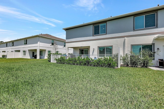 rear view of property featuring a lawn and stucco siding