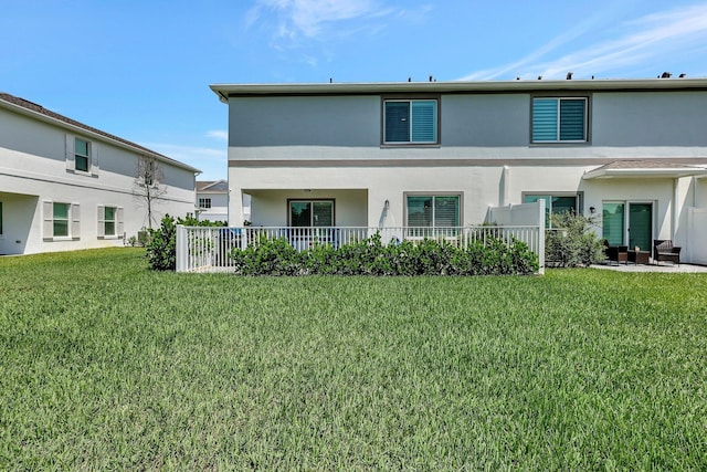 back of house featuring a lawn and stucco siding