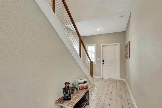 entrance foyer with light wood-type flooring, stairway, and baseboards