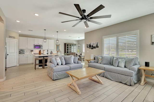 living area featuring light wood-style flooring, visible vents, ceiling fan, and recessed lighting