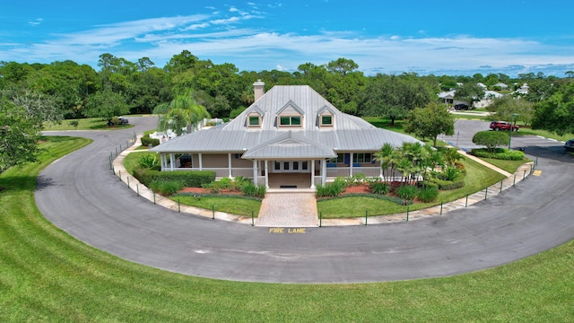 view of front of home featuring a chimney, metal roof, and a front yard