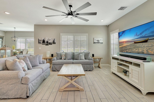 living room with wood tiled floor, visible vents, ceiling fan with notable chandelier, and recessed lighting