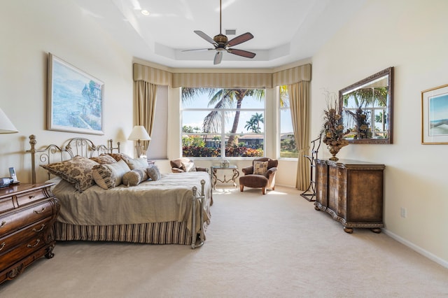 carpeted bedroom with ceiling fan, baseboards, and a raised ceiling