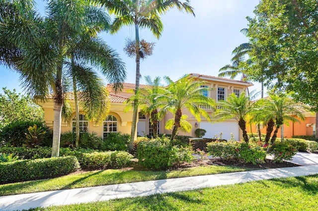 mediterranean / spanish-style home with a garage, a tiled roof, and stucco siding